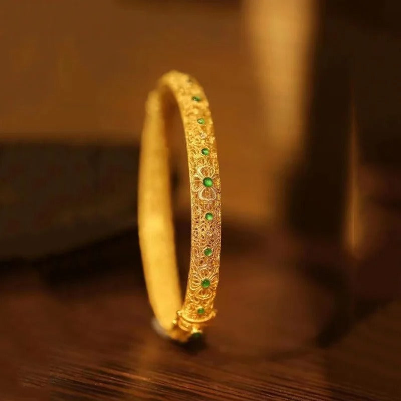 Złota bransoletka typu bangle z zielonymi kamieniami i etnicznym wzorem kwiatowym